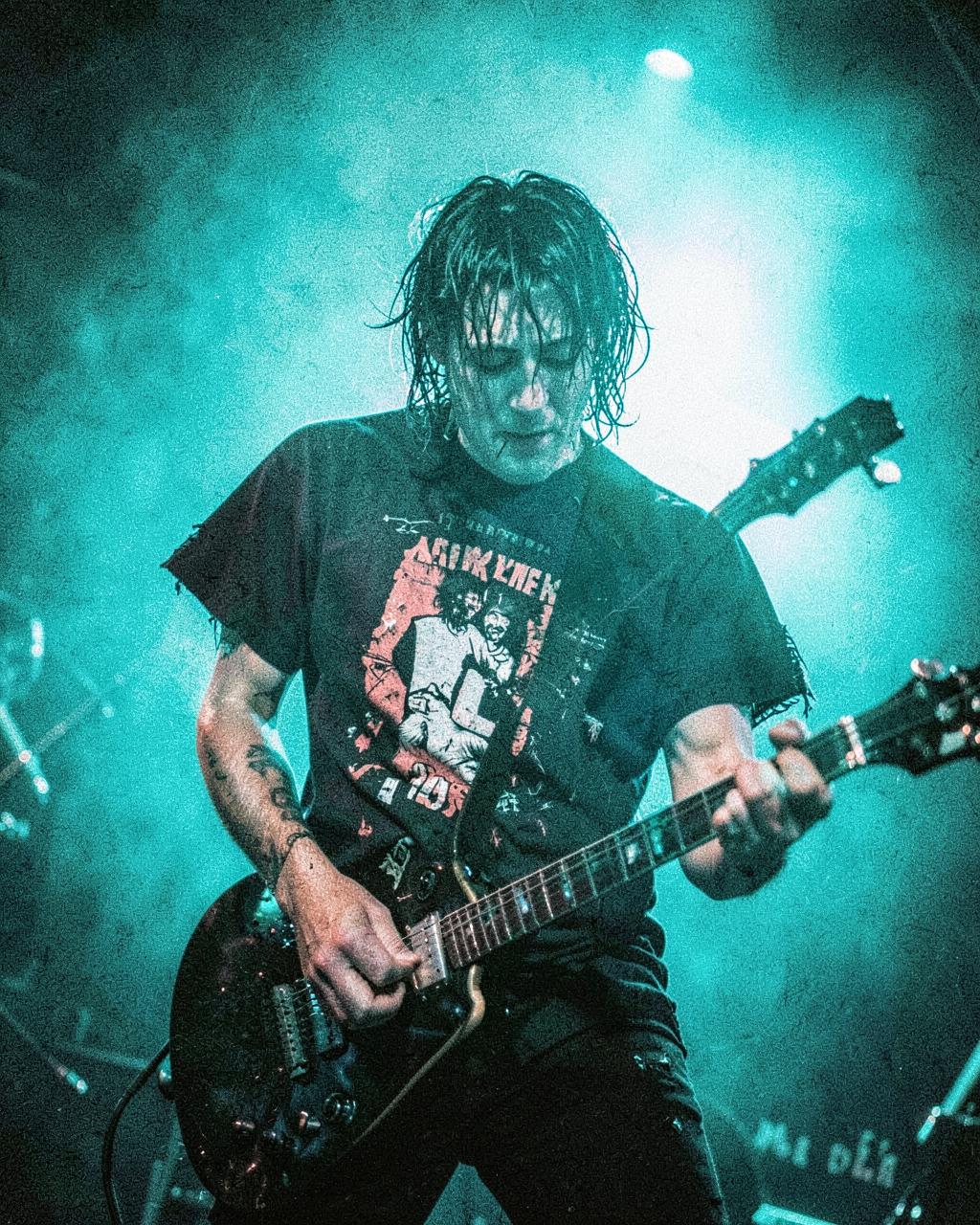 Punk guitarist Rue Halloway performing under neon backlight